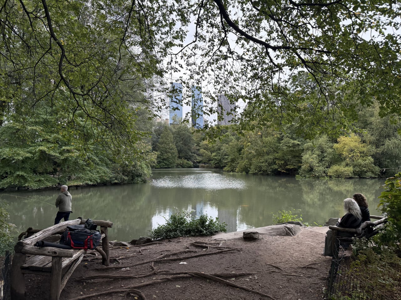 Pohled na jezírko v Central Parku, lidé sedí a rybaří u břehu