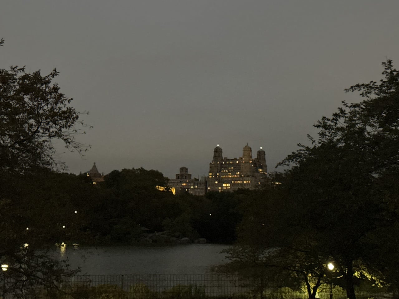 Večerní panorama Central Parku s osvětlenými budovami v dálce.