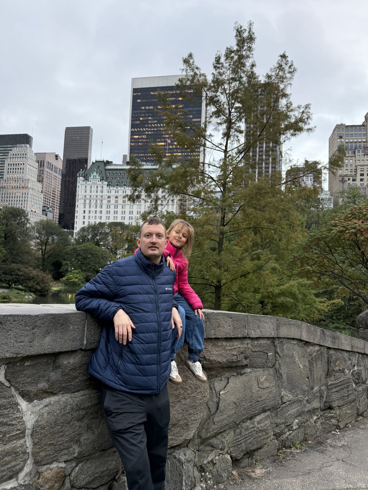 Muž s dítětem v Central Parku s výhledem na mrakodrapy New Yorku