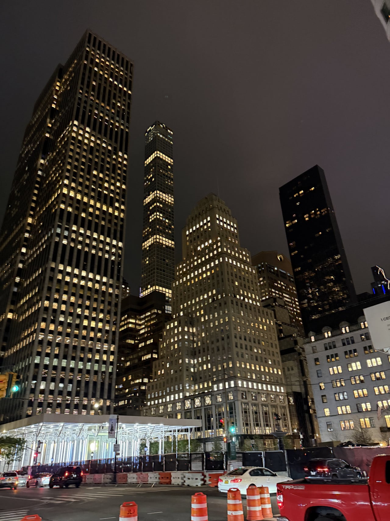 Noční panorama mrakodrapů v New Yorku s osvětlenými okny a auty dole