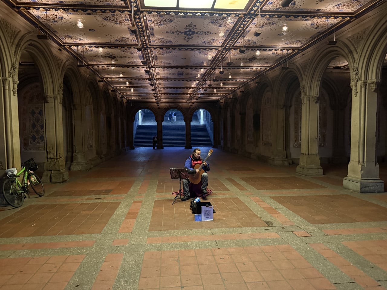 Pouliční kytarista hraje v podloubí Central Parku u schodů