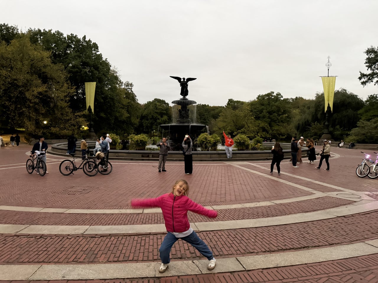 Dívka v růžové bundě pózuje před fontánou Bethesda v Central Parku.