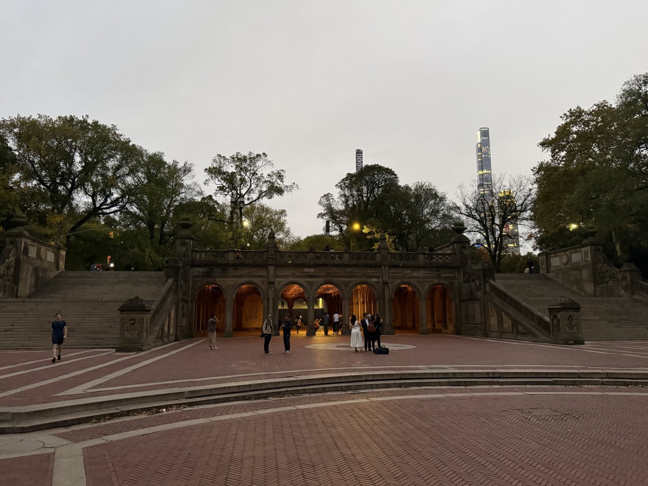 Terasa Bethesda v Central Parku za soumraku s lidmi a osvětleným podloubím