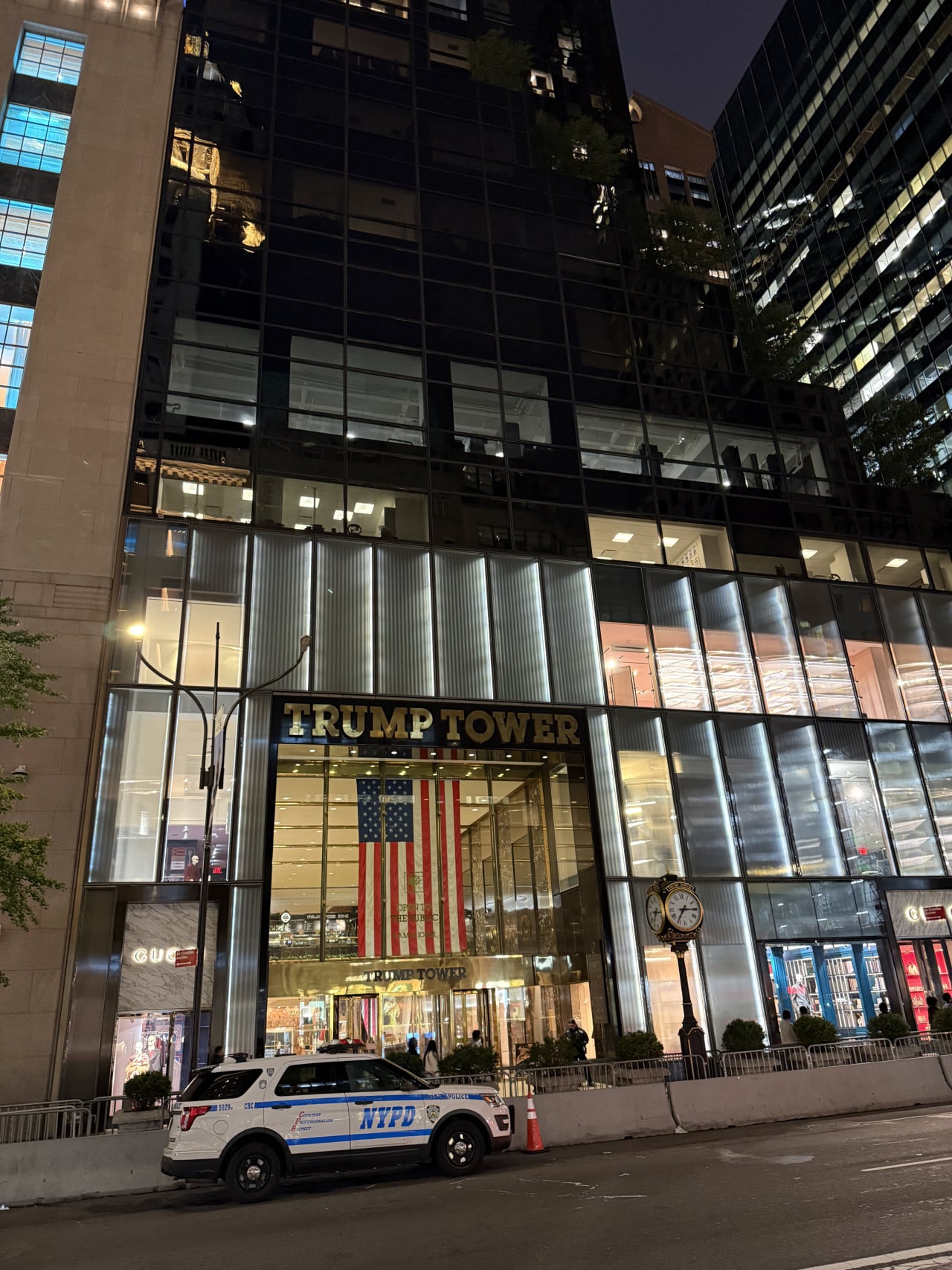 Noční pohled na Trump Tower s americkou vlajkou a policejním autem NYPD.