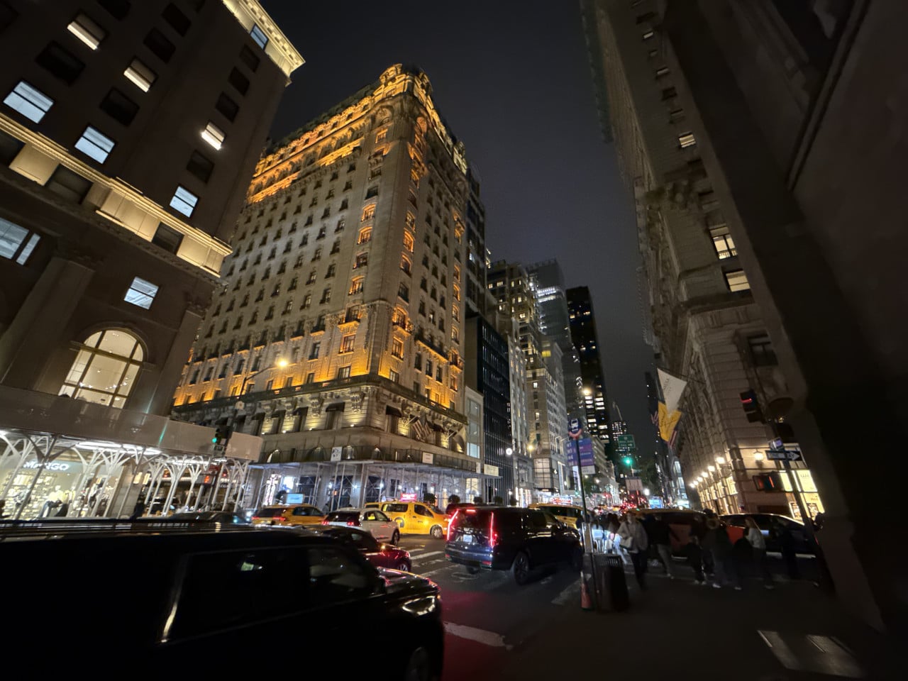 Noční ulice New Yorku s osvětleným historickým mrakodrapem a auty v provozu