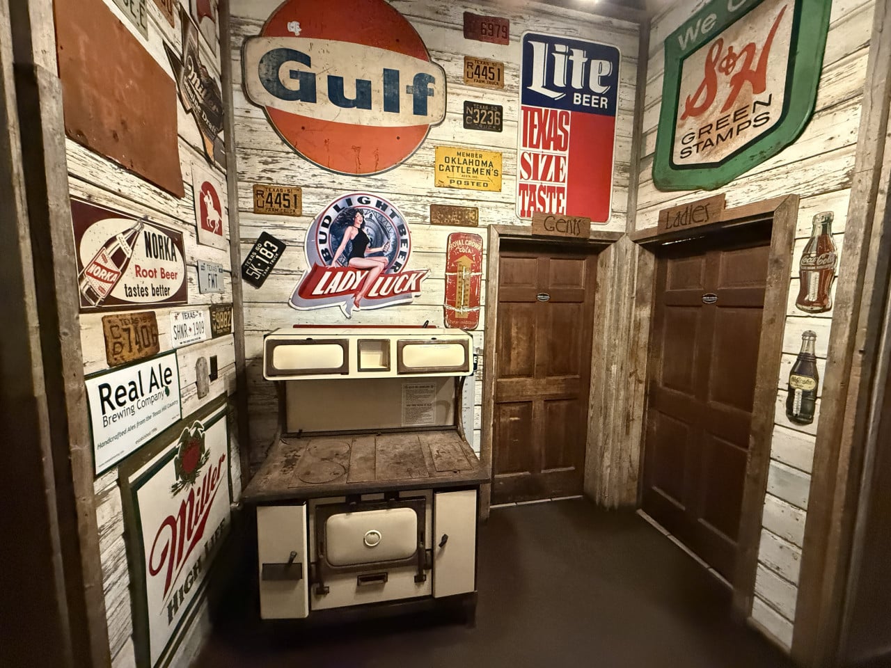 Rustikální koutek s kamny, dveře Ladies a Gents, cedule Gulf, Lite Beer