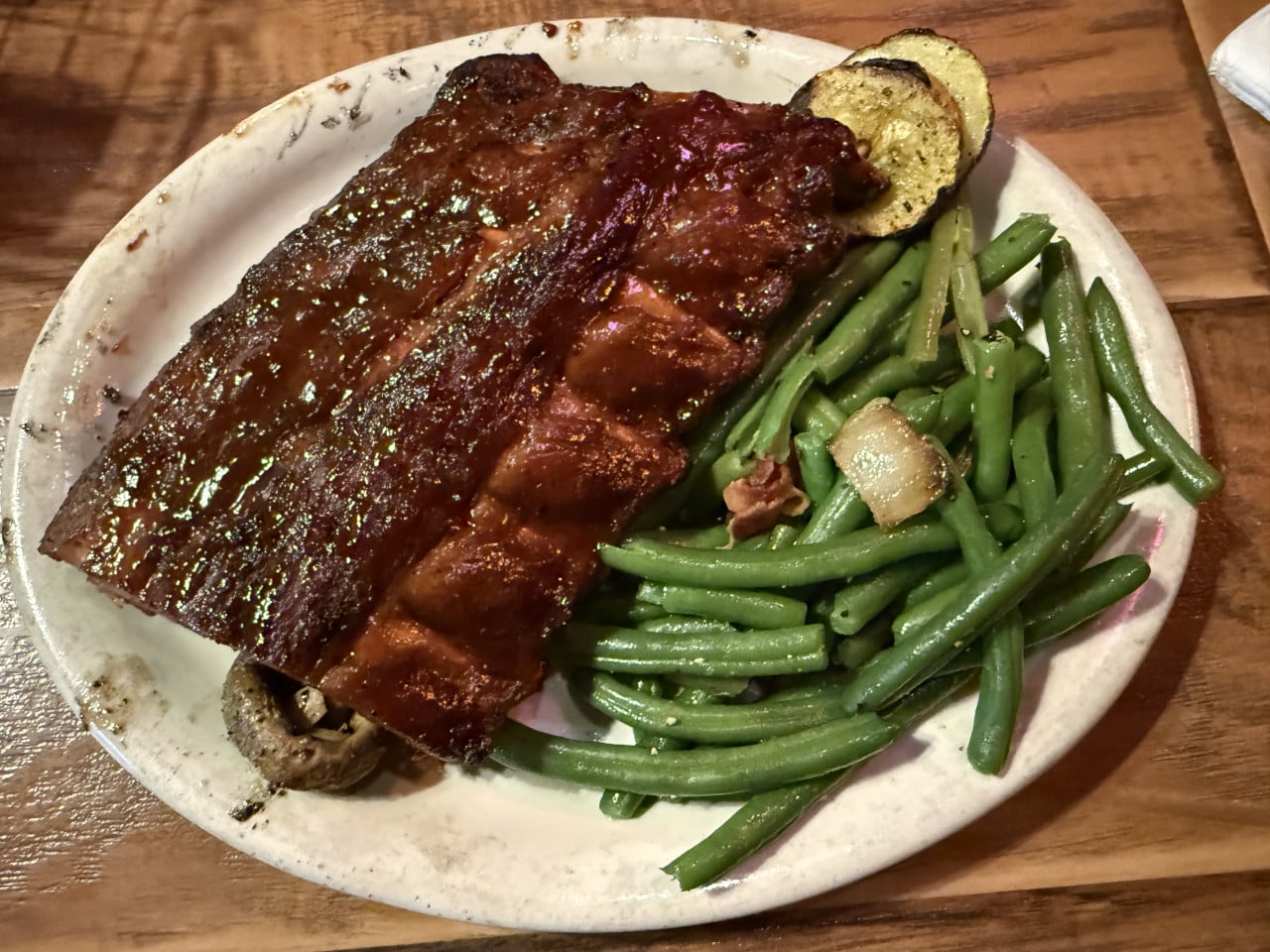 Talíř BBQ žebírek s omáčkou, zelenými fazolkami a grilovanou cuketou.