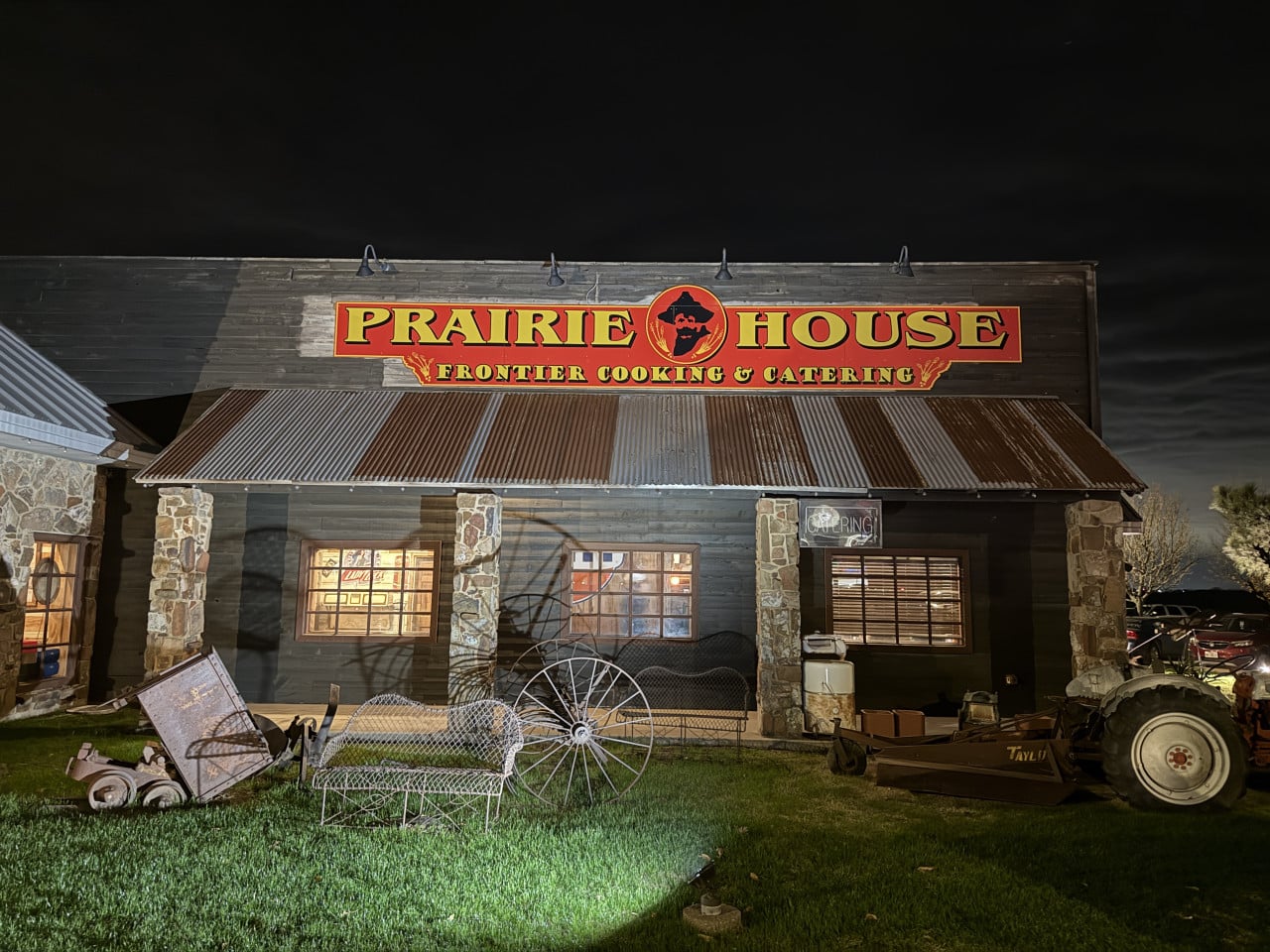 Noční pohled na budovu se cedulí PRAIRIE HOUSE FRONTIER COOKING & CATERING