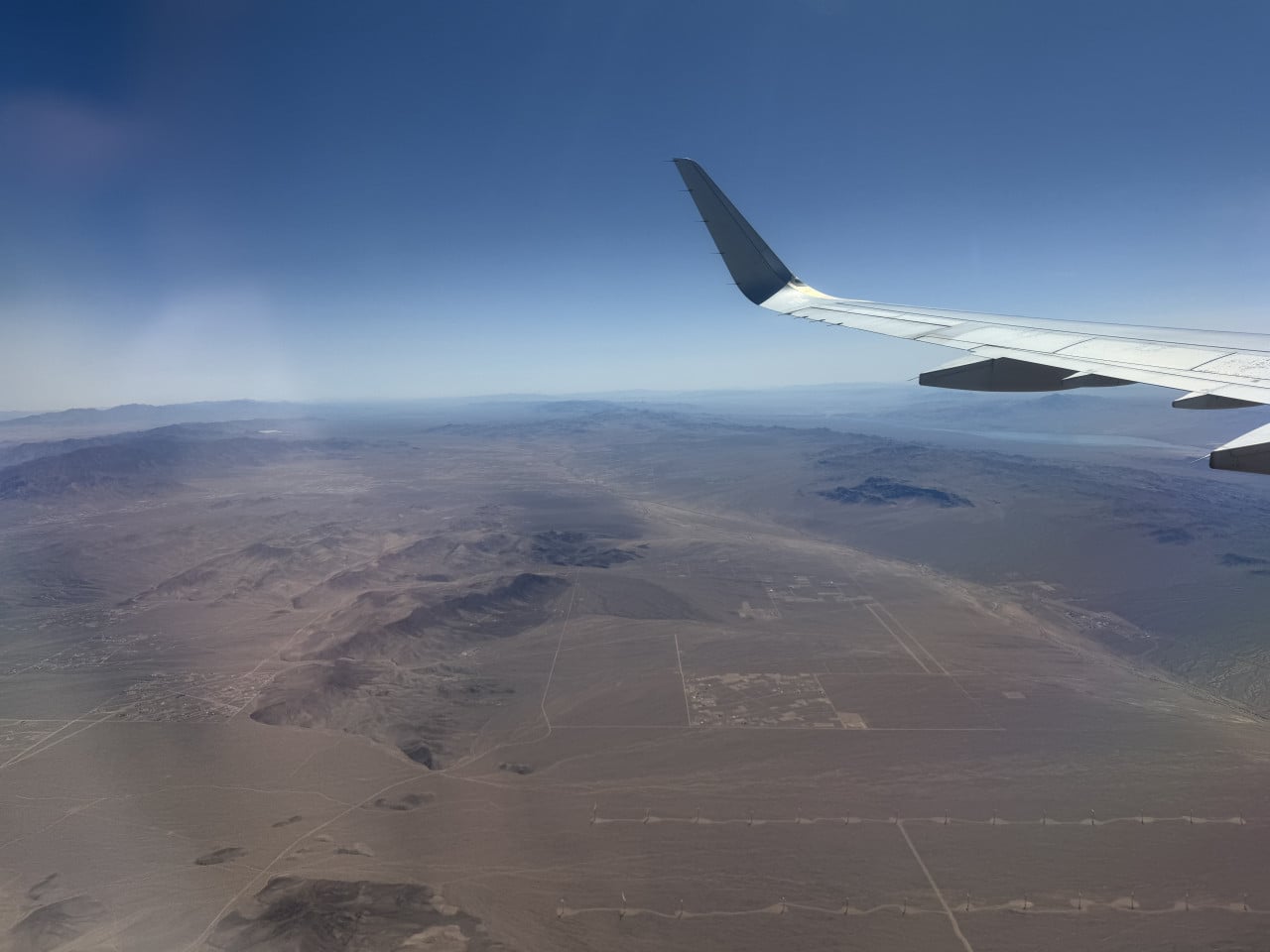 Pohled z letadla: křídlo nad pouštní krajinou a horami u Las Vegas.