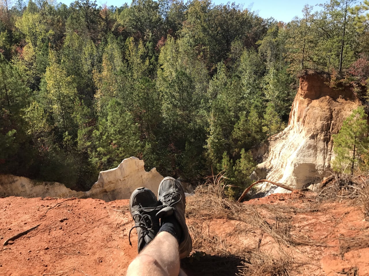 Pohled na Providence Canyon s nohama odpočívajícího turistu v popředí