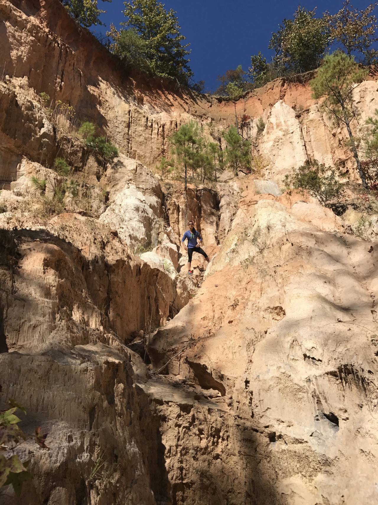 Člověk stojí mezi vysokými barevnými stěnami kaňonu v Providence Canyon.