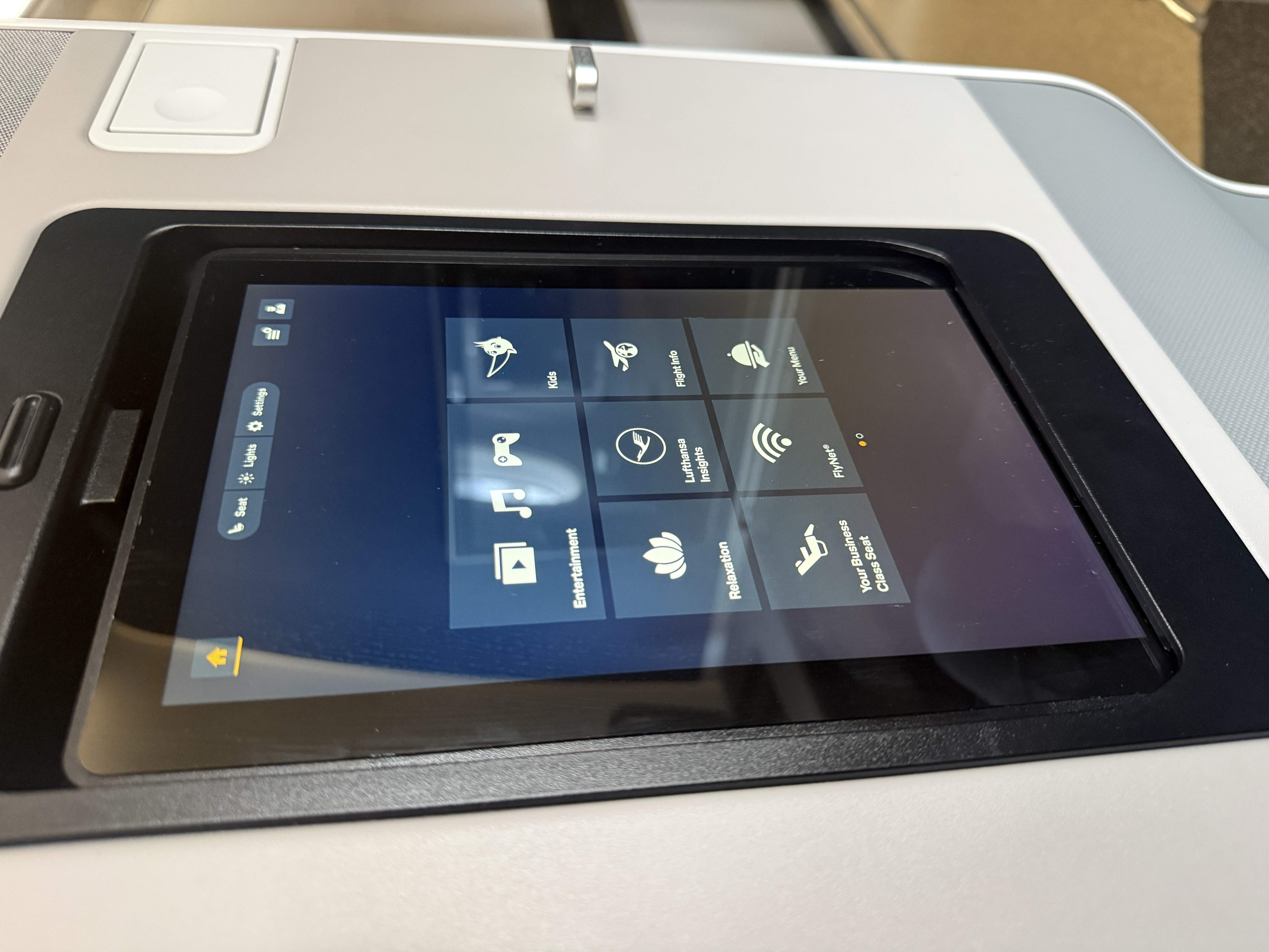 Displej palubní zábavy Lufthansa s menu: Entertainment, Your Business Class Seat, FlyNet, Your Menu