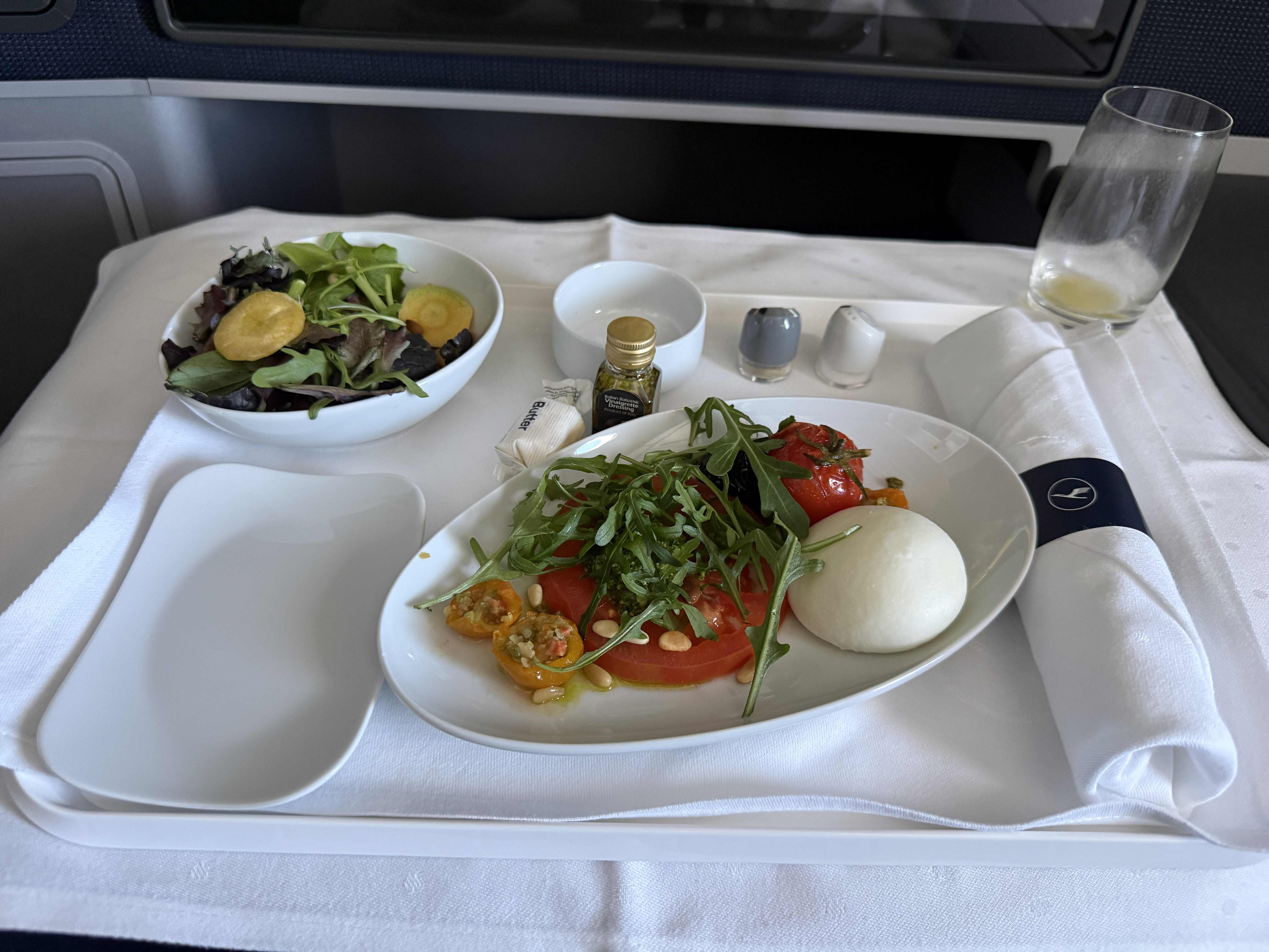 Servírovaný předkrm v business class Lufthansa: caprese, salát, olivový olej, sklenička