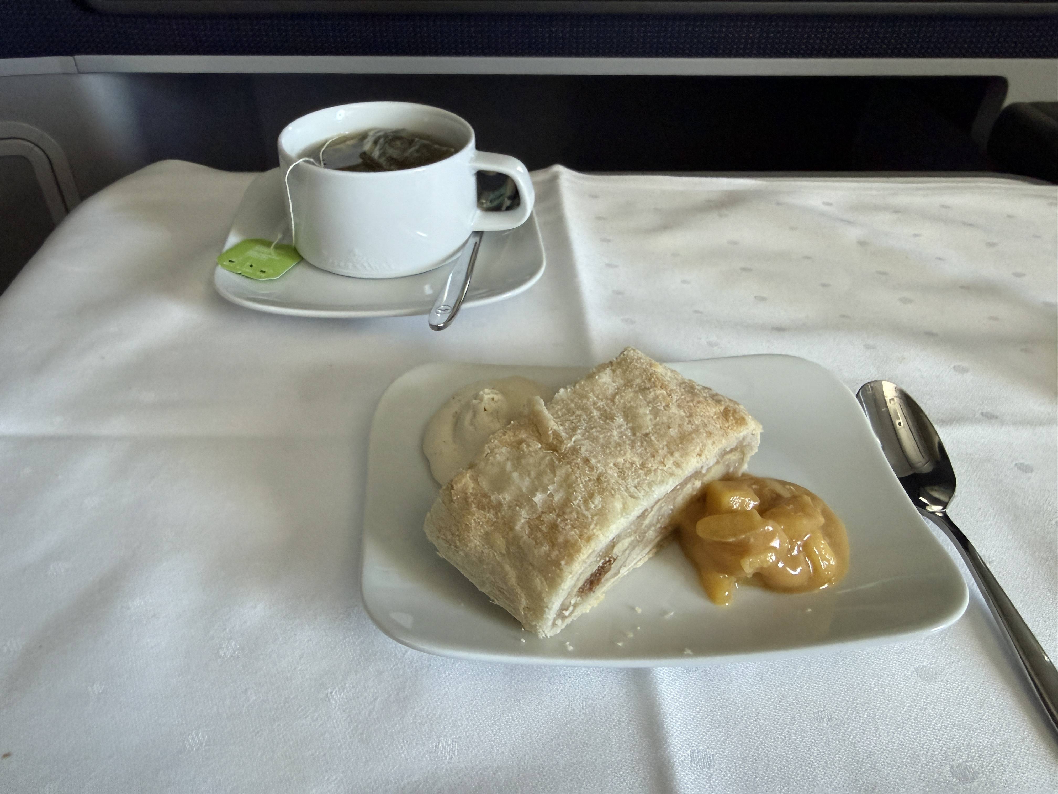 Šálek čaje a dezertní talířek se štrúdlem, krémem a ovocnou omáčkou na letadle.