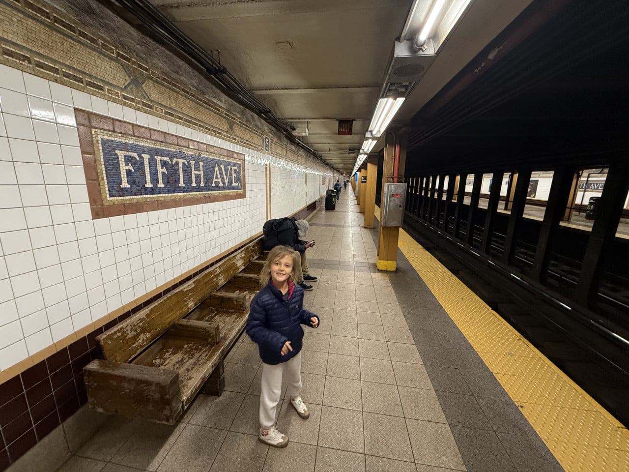 Stanice metra Fifth Ave s dívkou na perónu v New Yorku