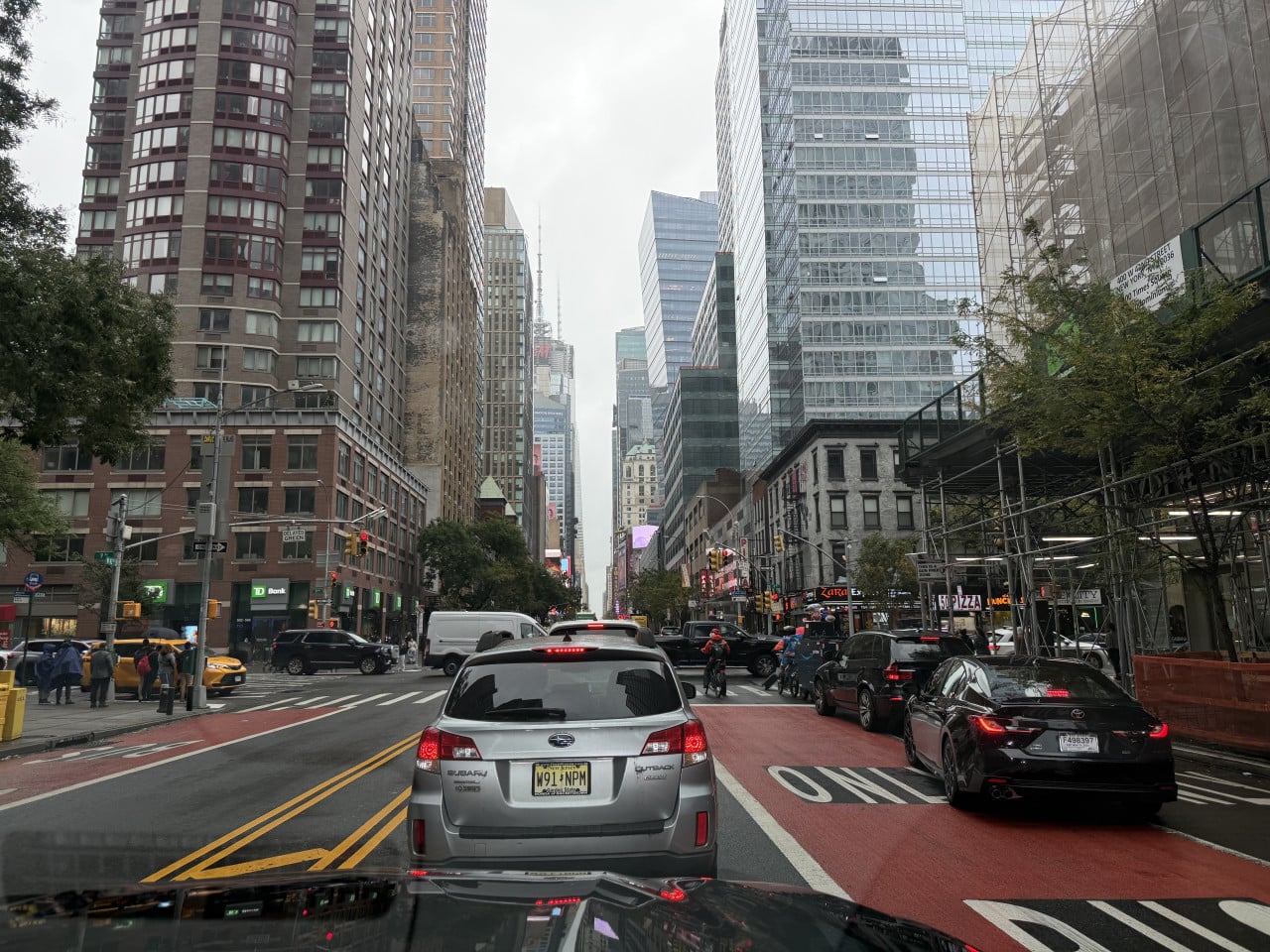 Doprava na manhattanské ulici mezi mrakodrapy v zataženém počasí