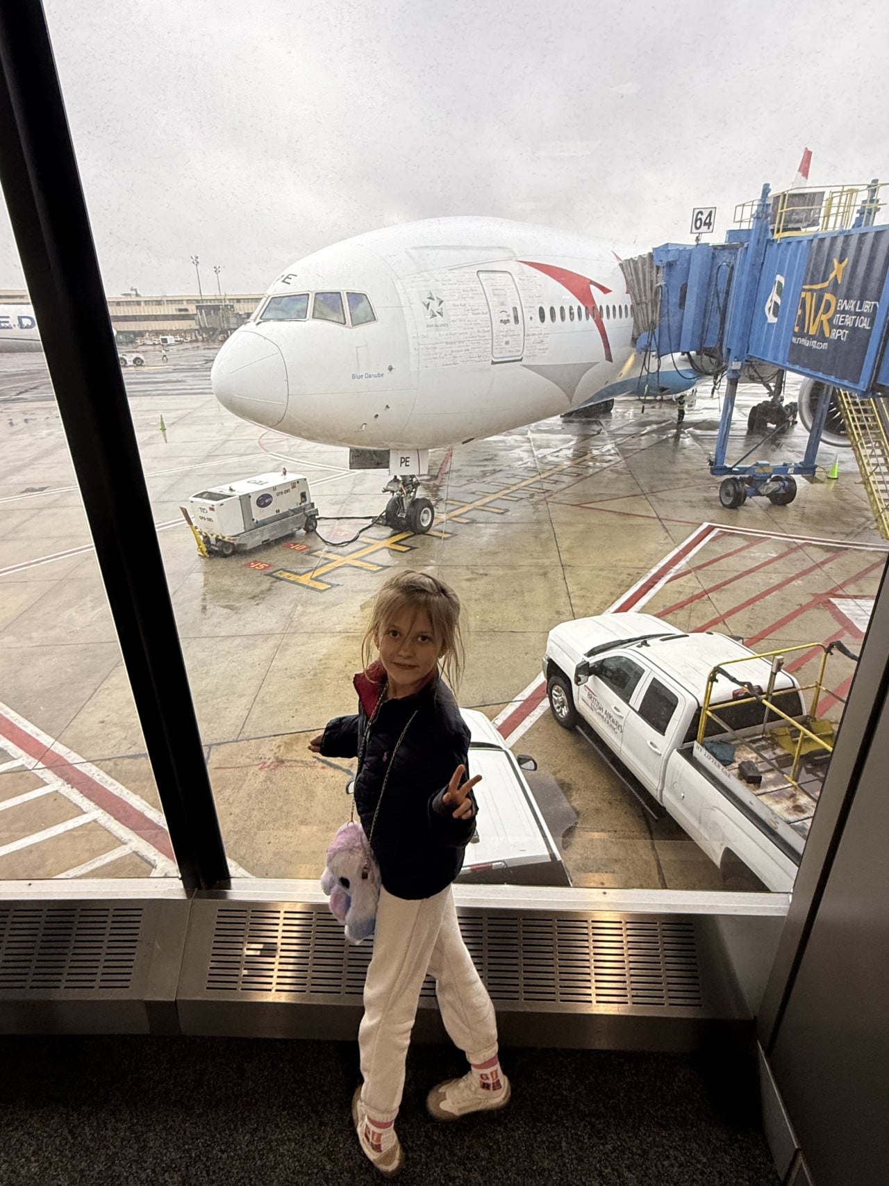 Dívka v letištním terminálu před letadlem u gate 64 na deštivém Newarku