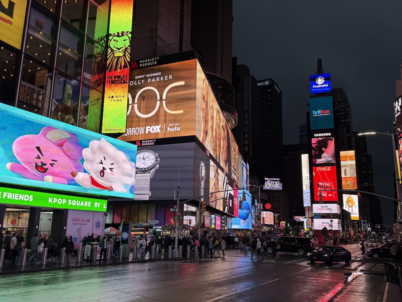 Večerní Times Square s osvícenými reklamními obrazovkami a lidmi na ulici