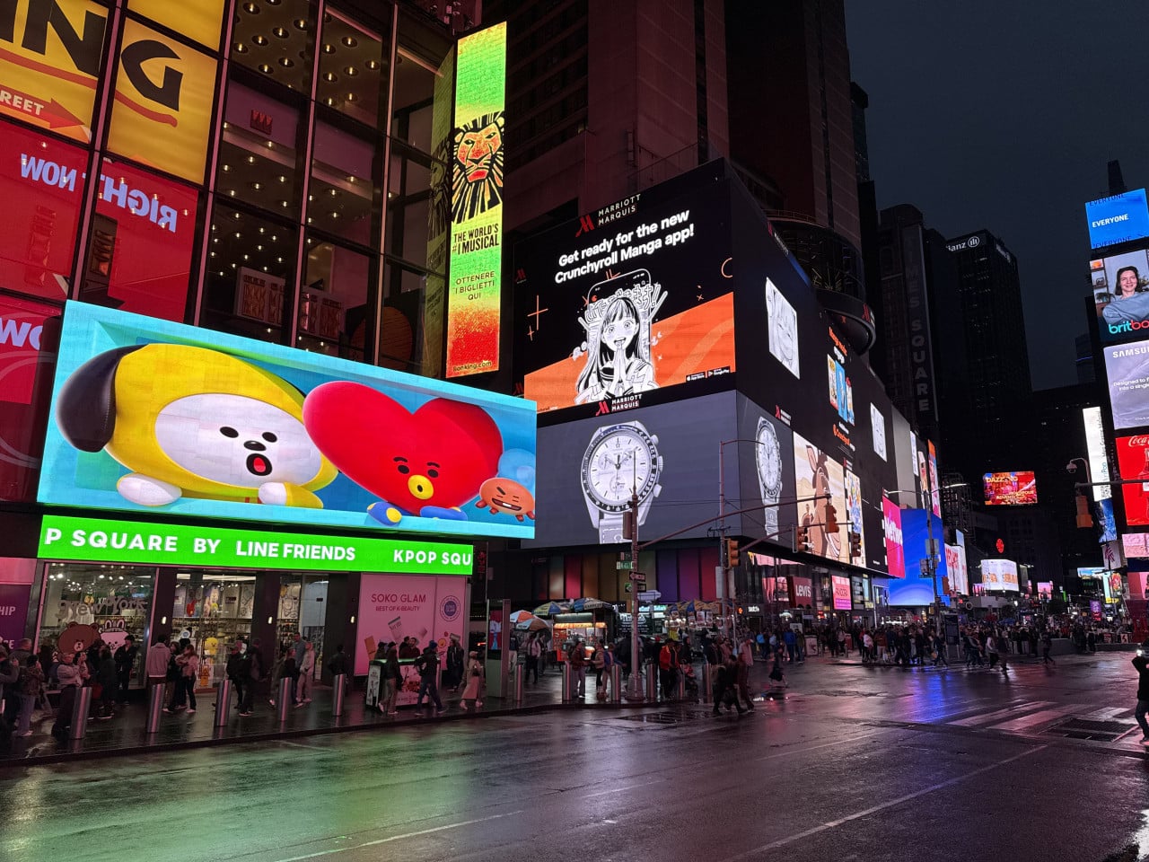 Noční Times Square s barevnými billboardy a lidmi na mokré ulici