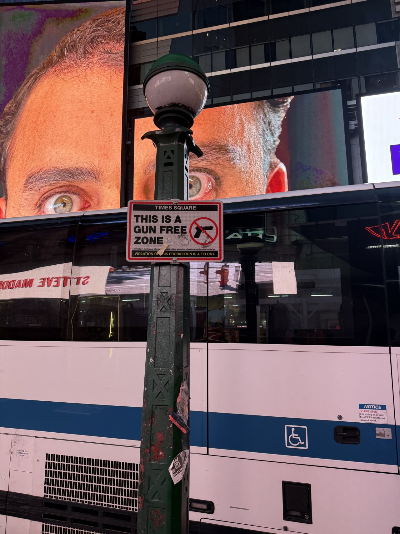 Times Square s velkou reklamou, lampou a cedulí This is a gun free zone