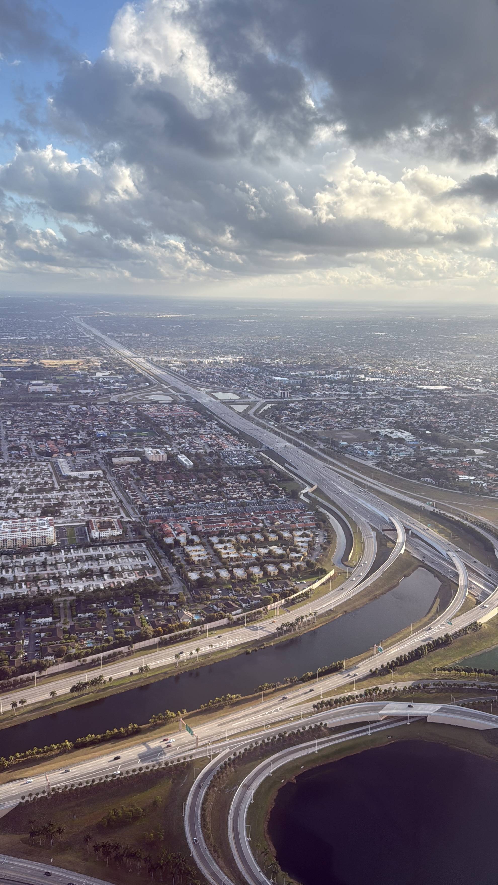 Letecký pohled na město, dálniční křižovatku a kanál pod dramatickou oblohou.