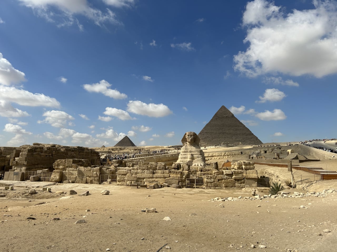 Pohled na Sfinxu a Cheopsovu pyramidu pod modrou oblohou v Gíze
