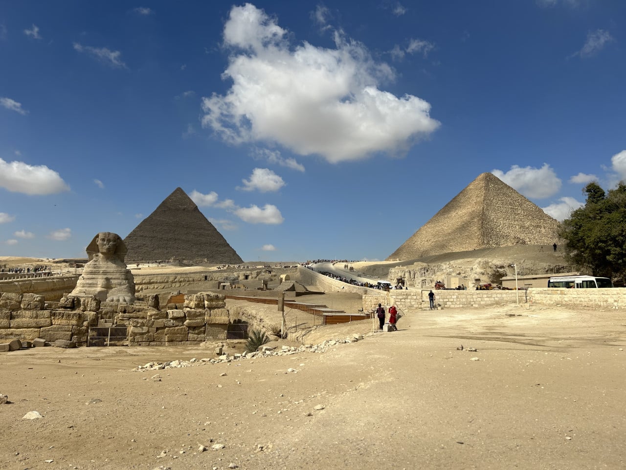 Pyramidy v Gíze se Sfingou, turisty a modrou oblohou s mraky