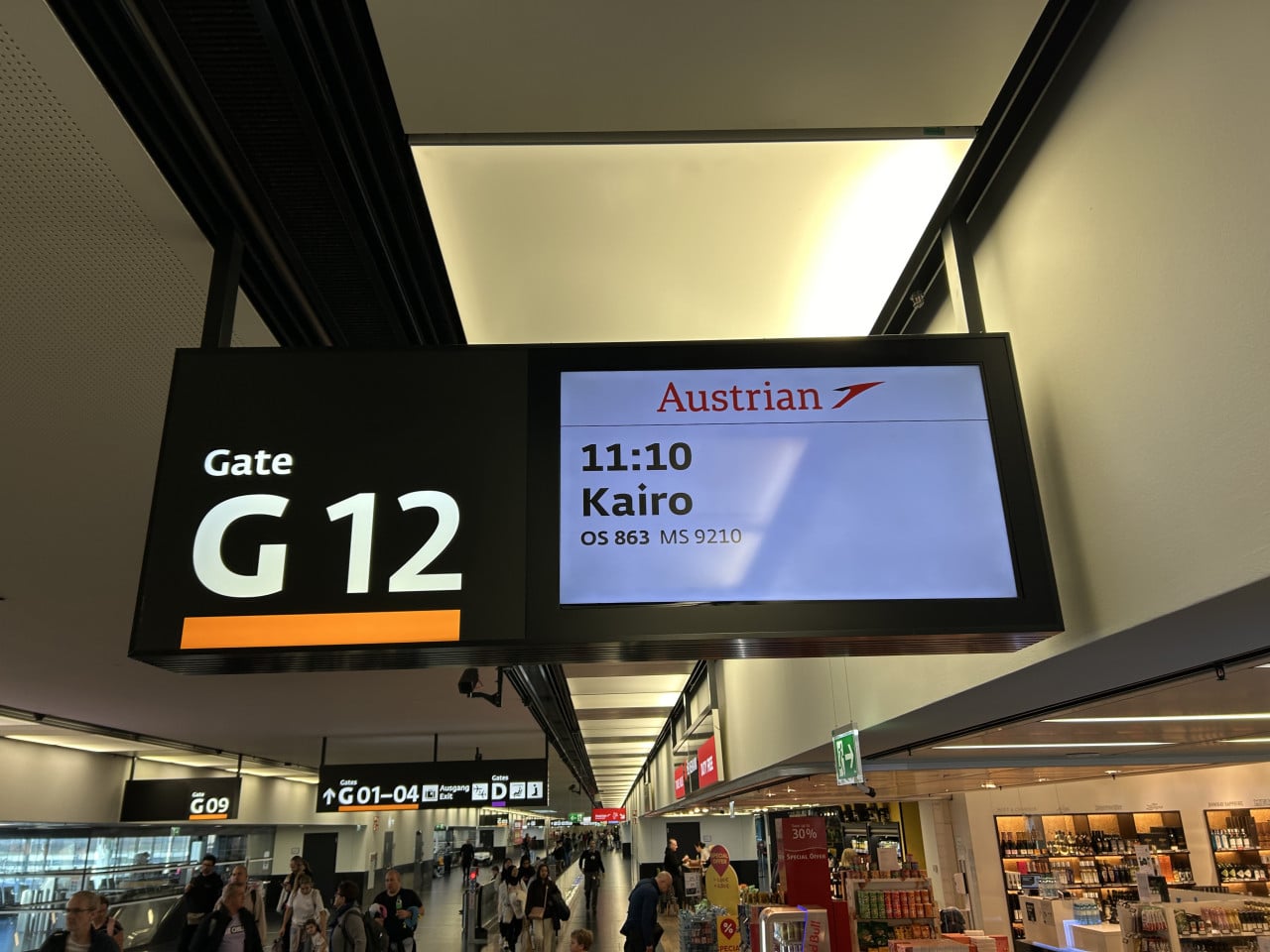 Letištní odletová tabule u gate G12, let Austrian do Káhiry.