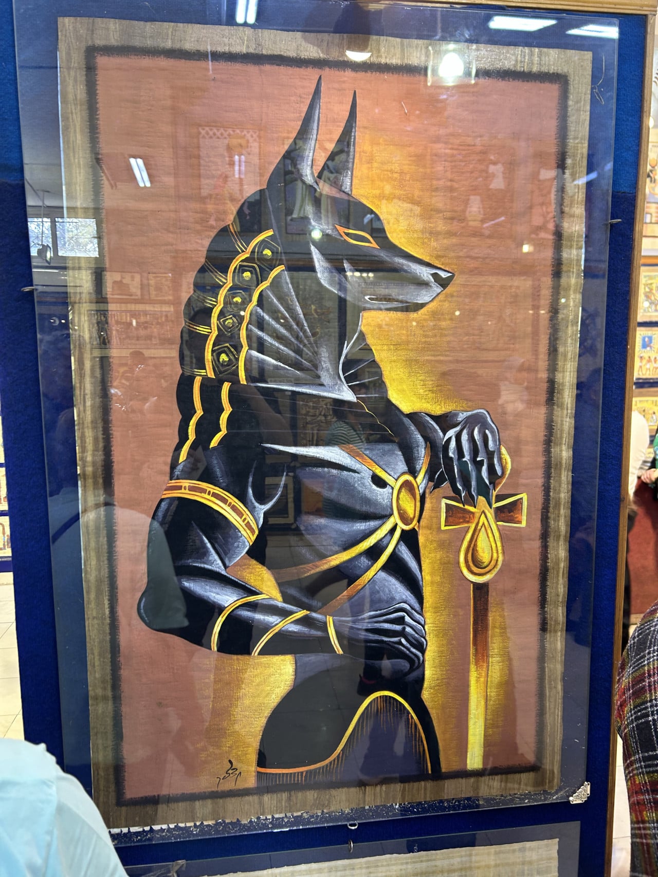 Malba egyptského boha Anubise s ankhem ve vitríně muzea