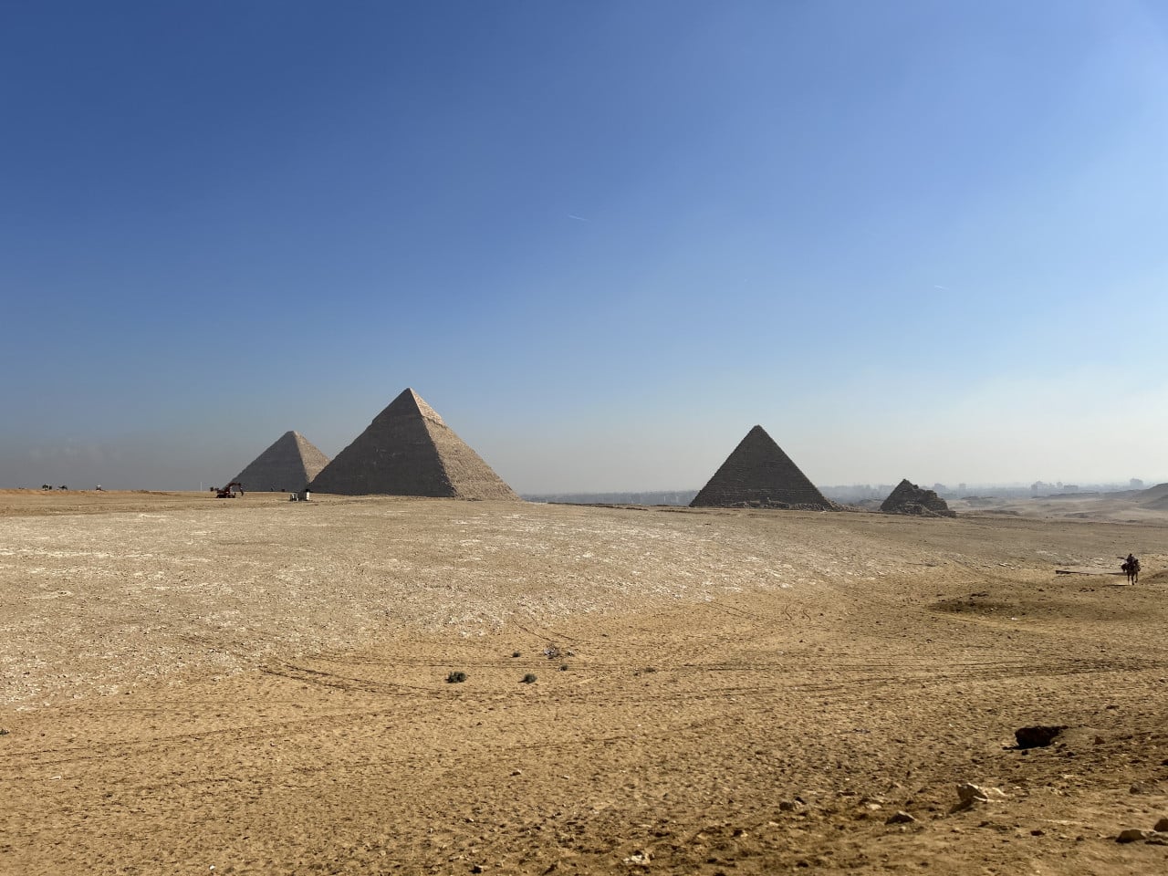 Tři pyramidy v Gíze na pouštní pláni pod modrou oblohou