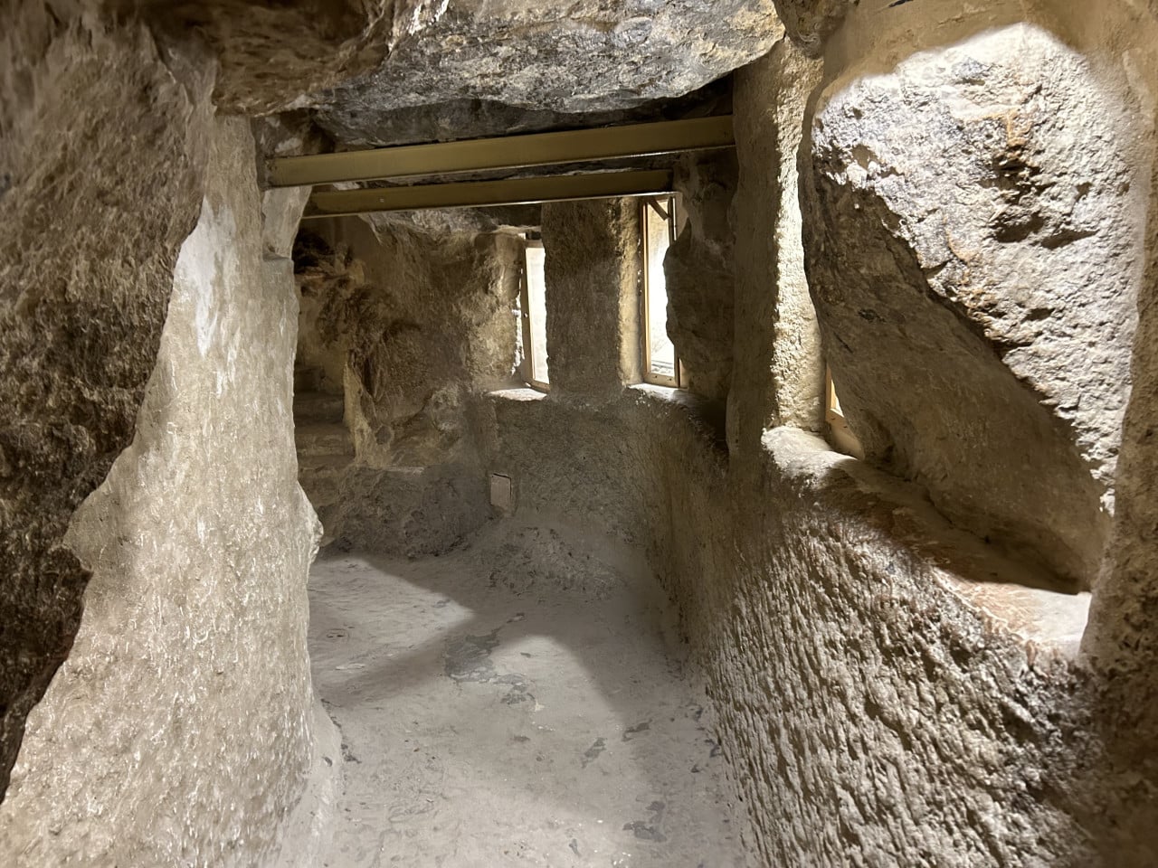 Úzká kamenná chodba uvnitř pyramidy s okny a podpěrnými trámy.
