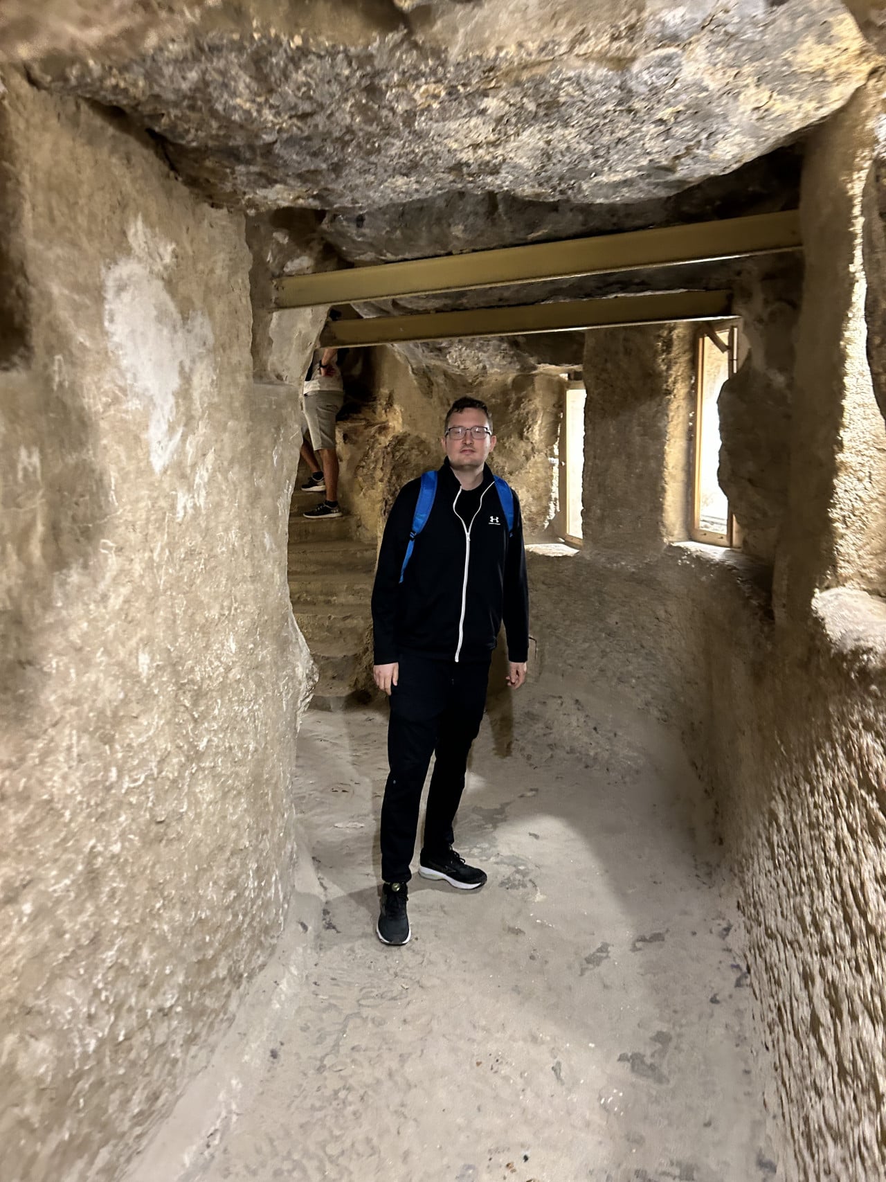 Muž uvnitř úzké kamenné chodby Cheopsovy pyramidy v Gíze.