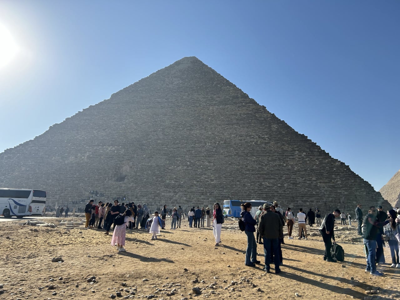 Cheopsova pyramida v Gíze s turisty a autobusy pod modrou oblohou