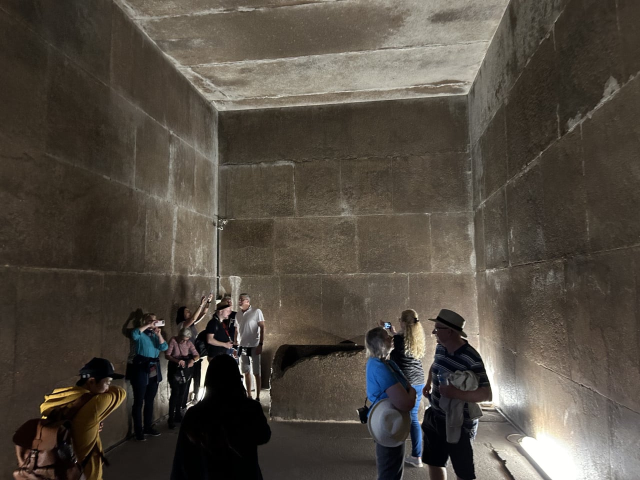 Turisté uvnitř Cheopsovy pyramidy v úzké kamenné komoře.
