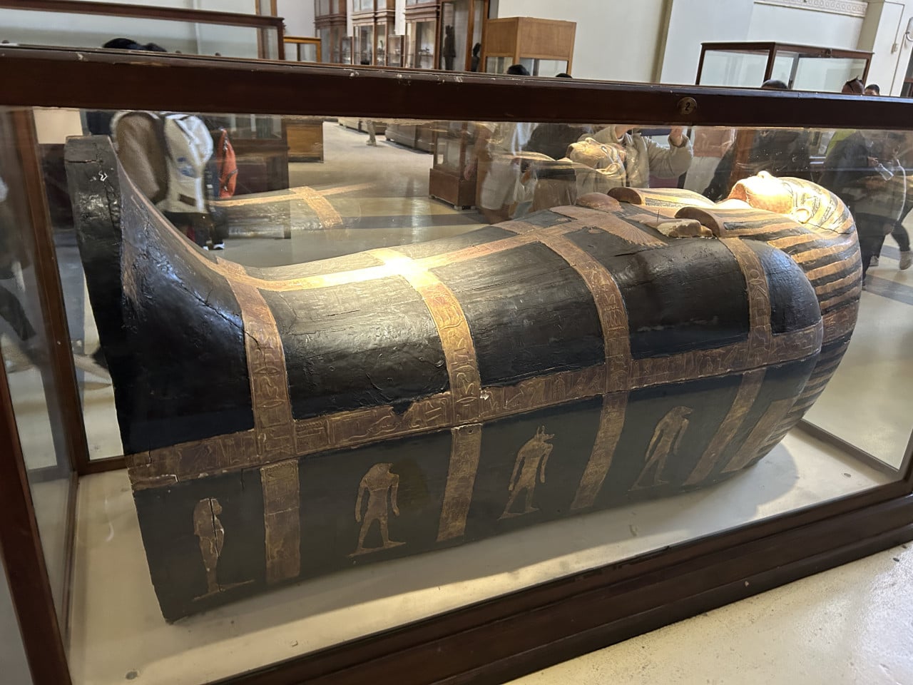 Egyptská dřevěná rakvová schránka s malovanými hieroglyfy v muzeální vitríně