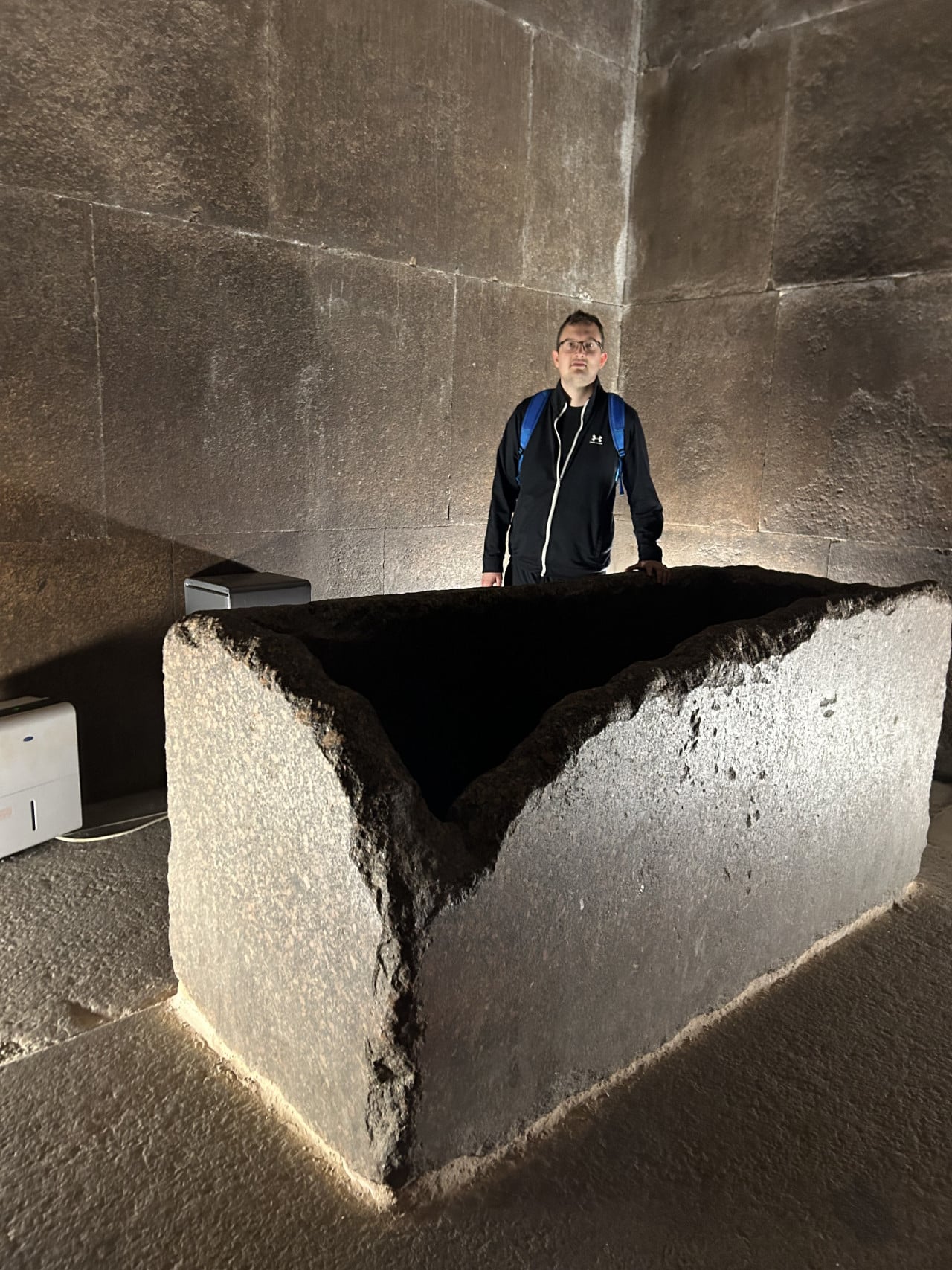 Muž stojí v Cheopsově pyramidě u kamenné sarkofágové truhly.