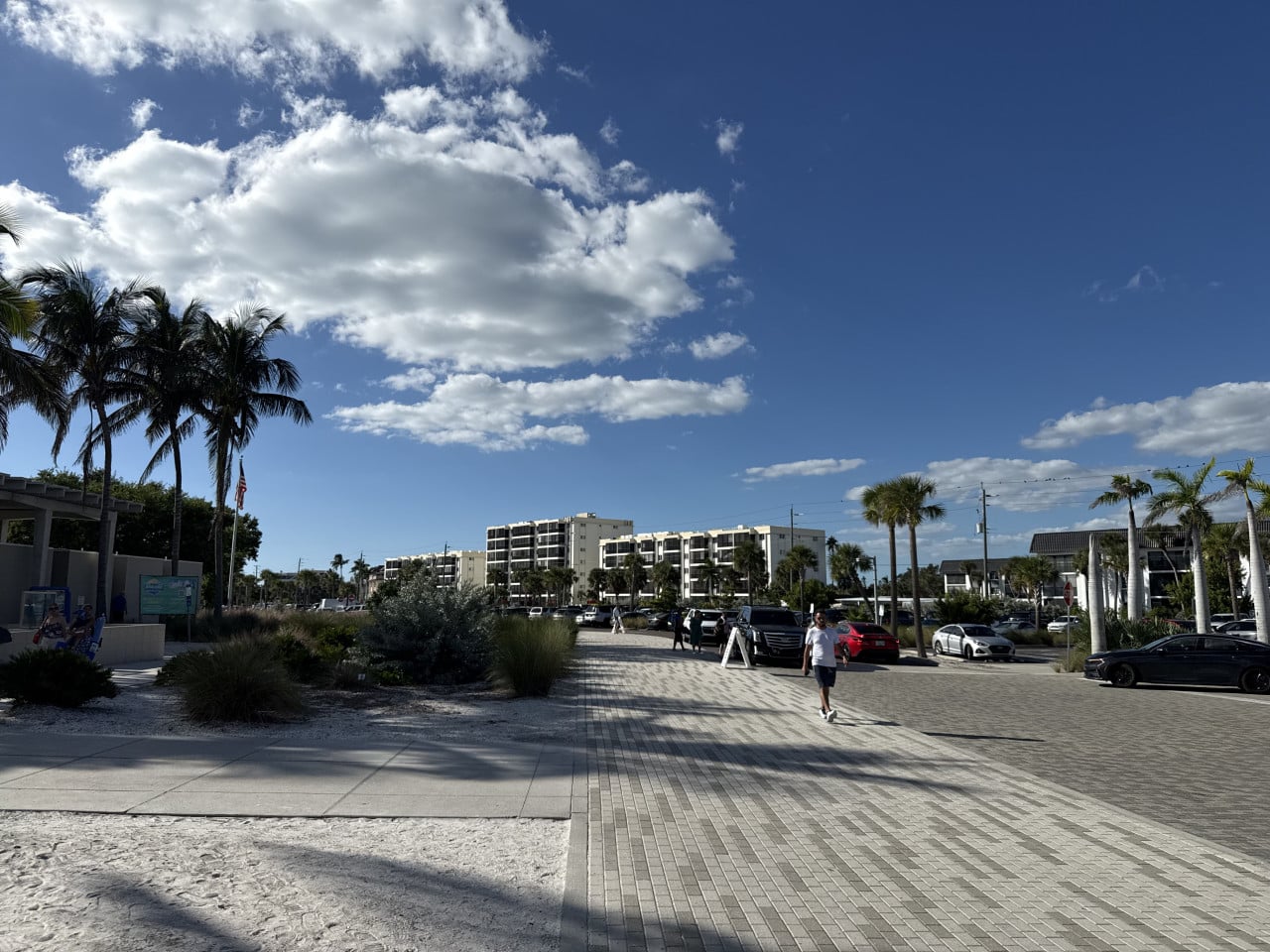 Vstup na Siesta Key Beach s palmami, parkovištěm a modrou oblohou s mraky