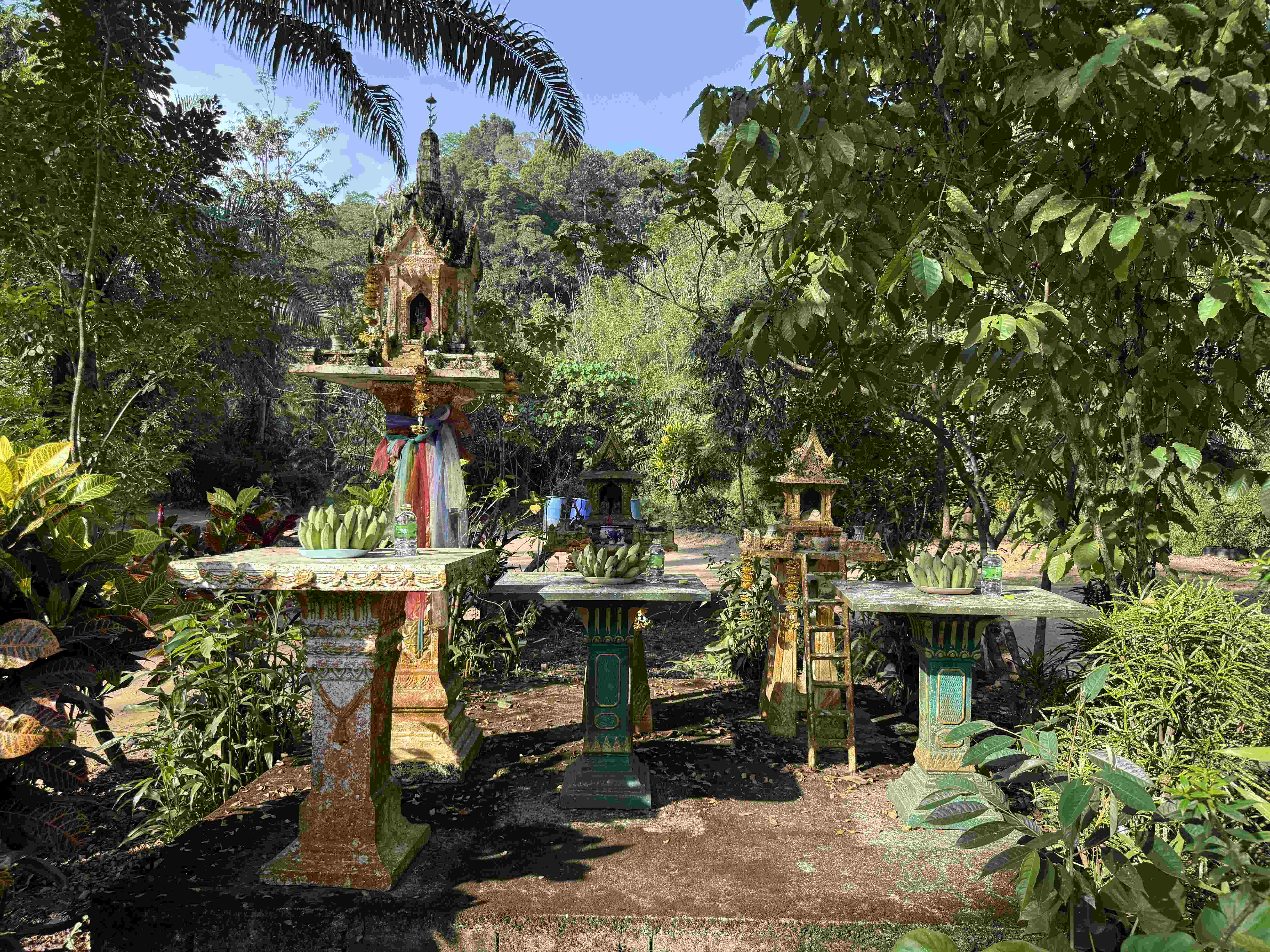 Buddhistická svatyně v džungli, na oltářích banány a lahve s vodou