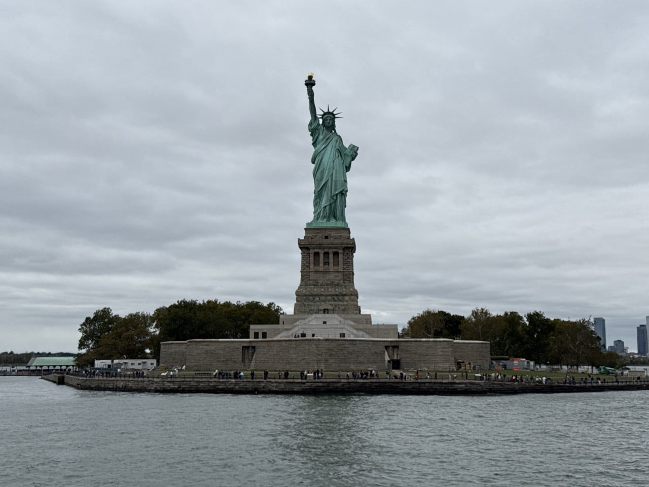 Socha Svobody na ostrově Liberty Island, pohled z vody pod zataženou oblohou