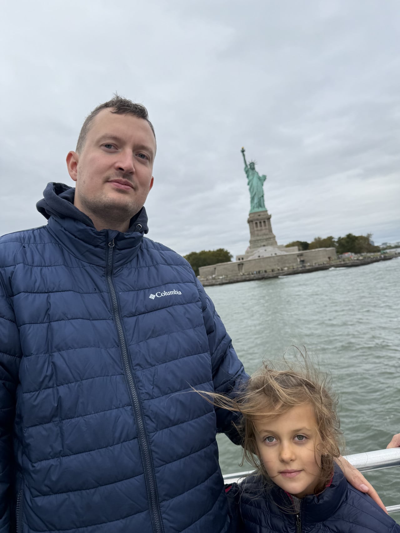 Muž a dítě na lodi před Sochou Svobody v New Yorku.