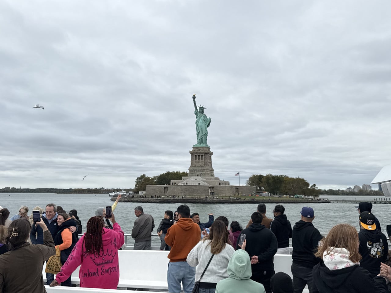 Socha Svobody na ostrově, pozorovaná z plné turistické lodi.
