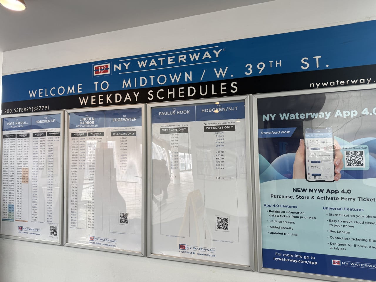 Nástěnka jízdních řádů NY Waterway s informacemi o trajektech a QR kódem.