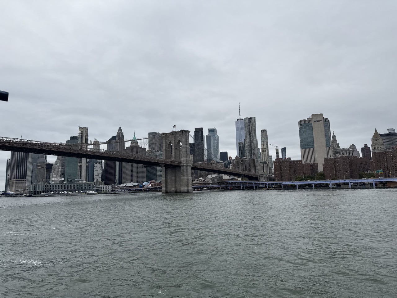 Brooklyn Bridge nad řekou, panorama Dolního Manhattanu s One World Trade Center.