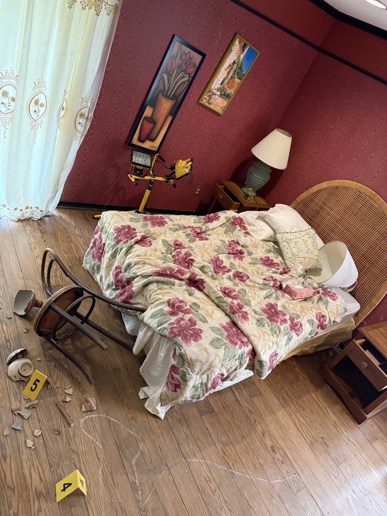 Ložnice s postelí s květovanou přikrývkou, převrženou židlí, křídou a značkami 4 a 5.