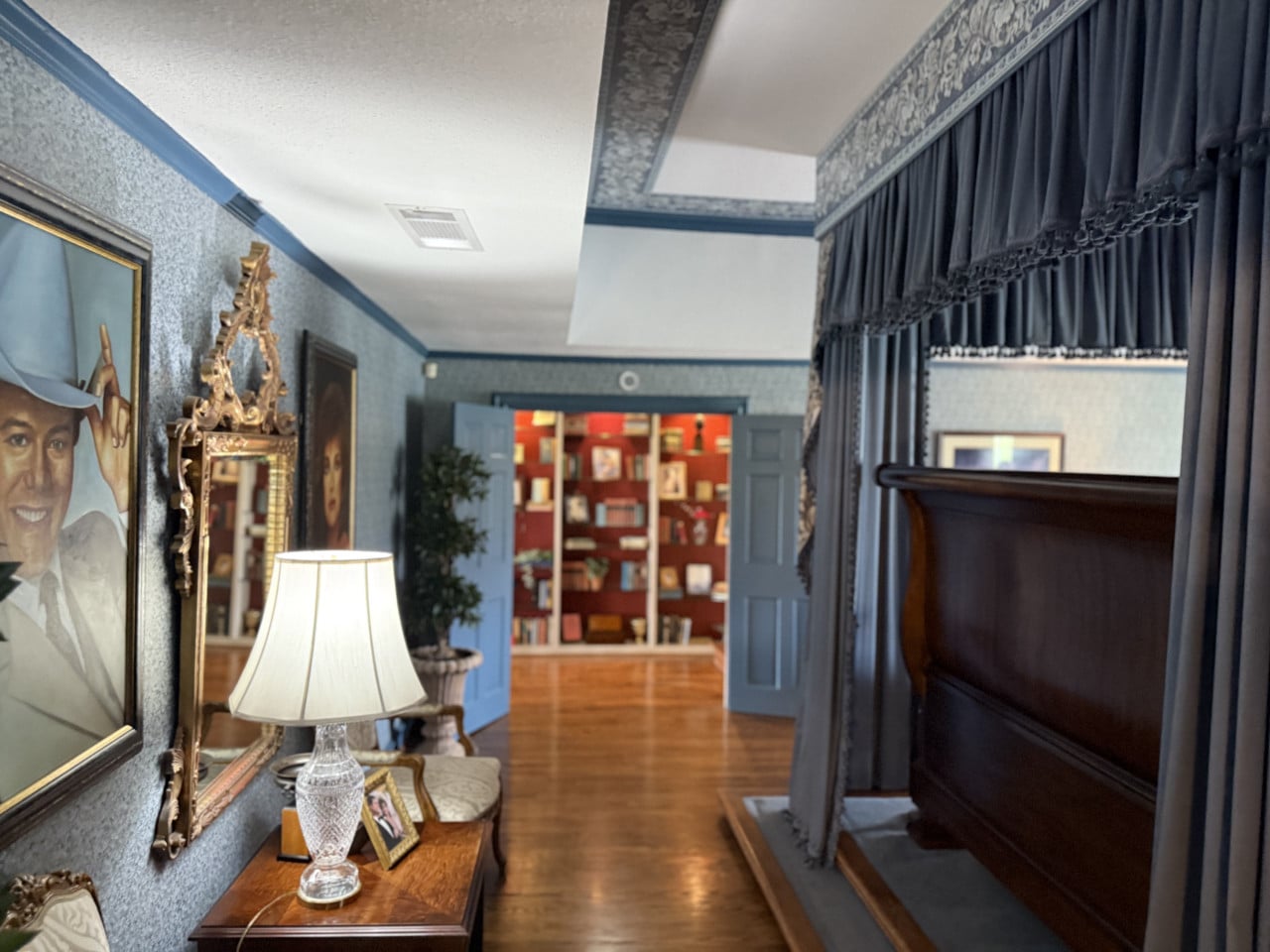 Interiér ložnice na Southfork Ranch s baldachýnem, lampou a otevřenými dveřmi k knihovně.