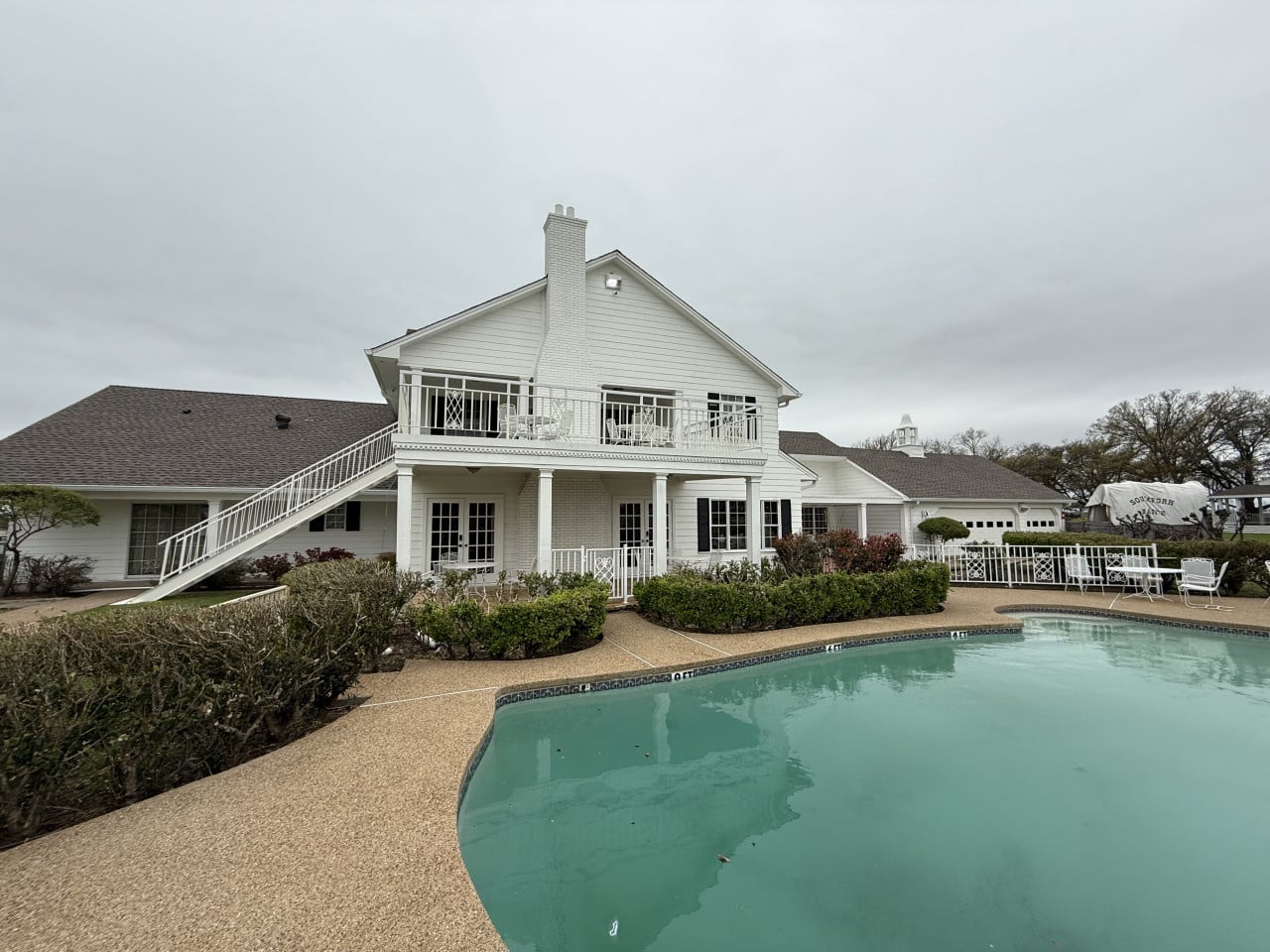 Bílý dům Southfork Ranch s balkonem a bazénem, nápis SOUTHFORK RANCH.