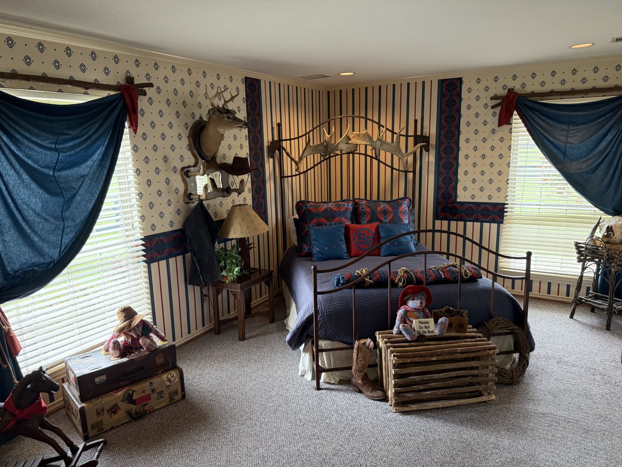 Ložnice na ranči: postel s parohy, vycpaná hlava jelena, Please Do Not Sit On Bed.