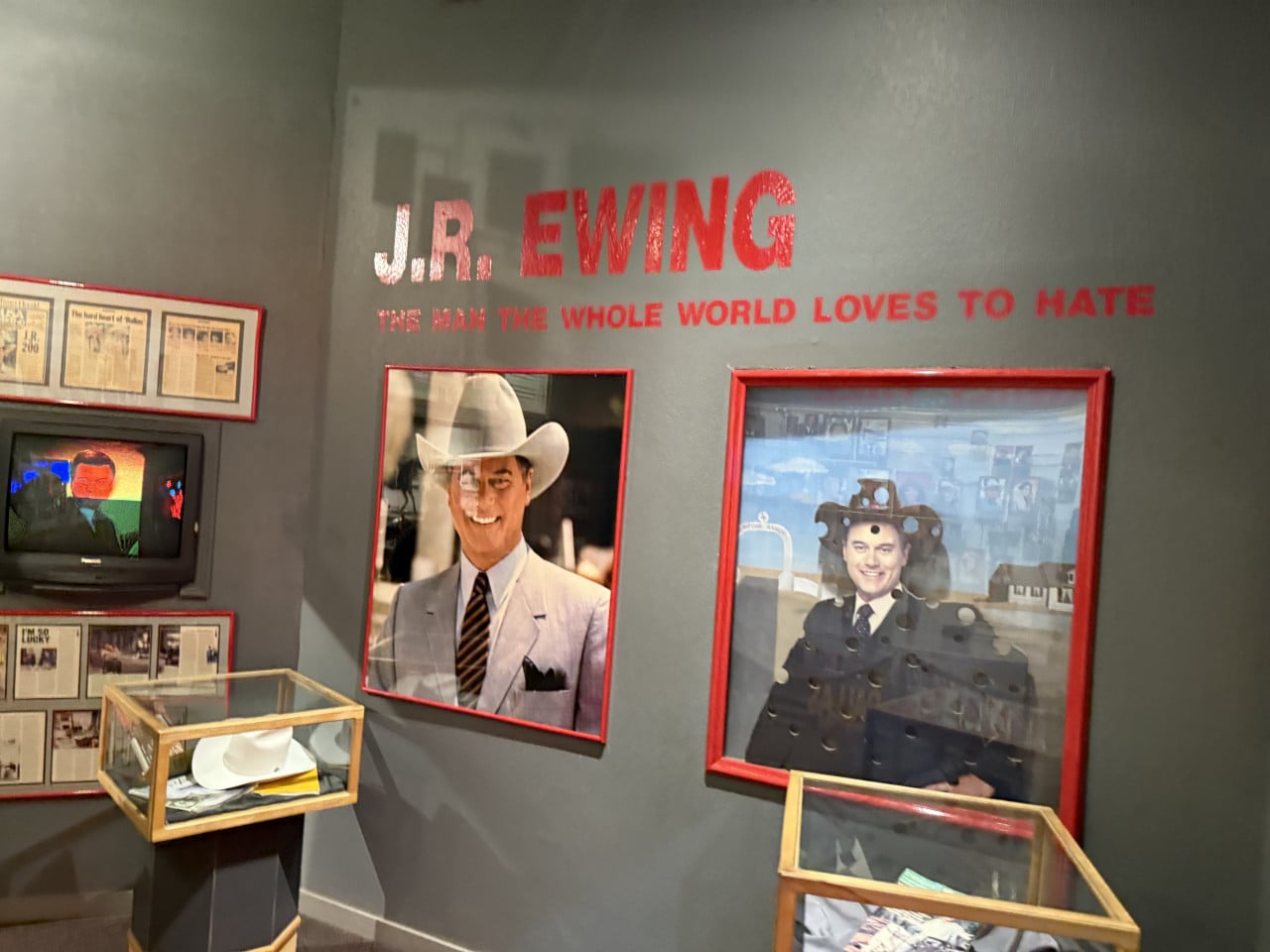 Stěna expozice s nápisem J.R. EWING a THE MAN THE WHOLE WORLD LOVES TO HATE