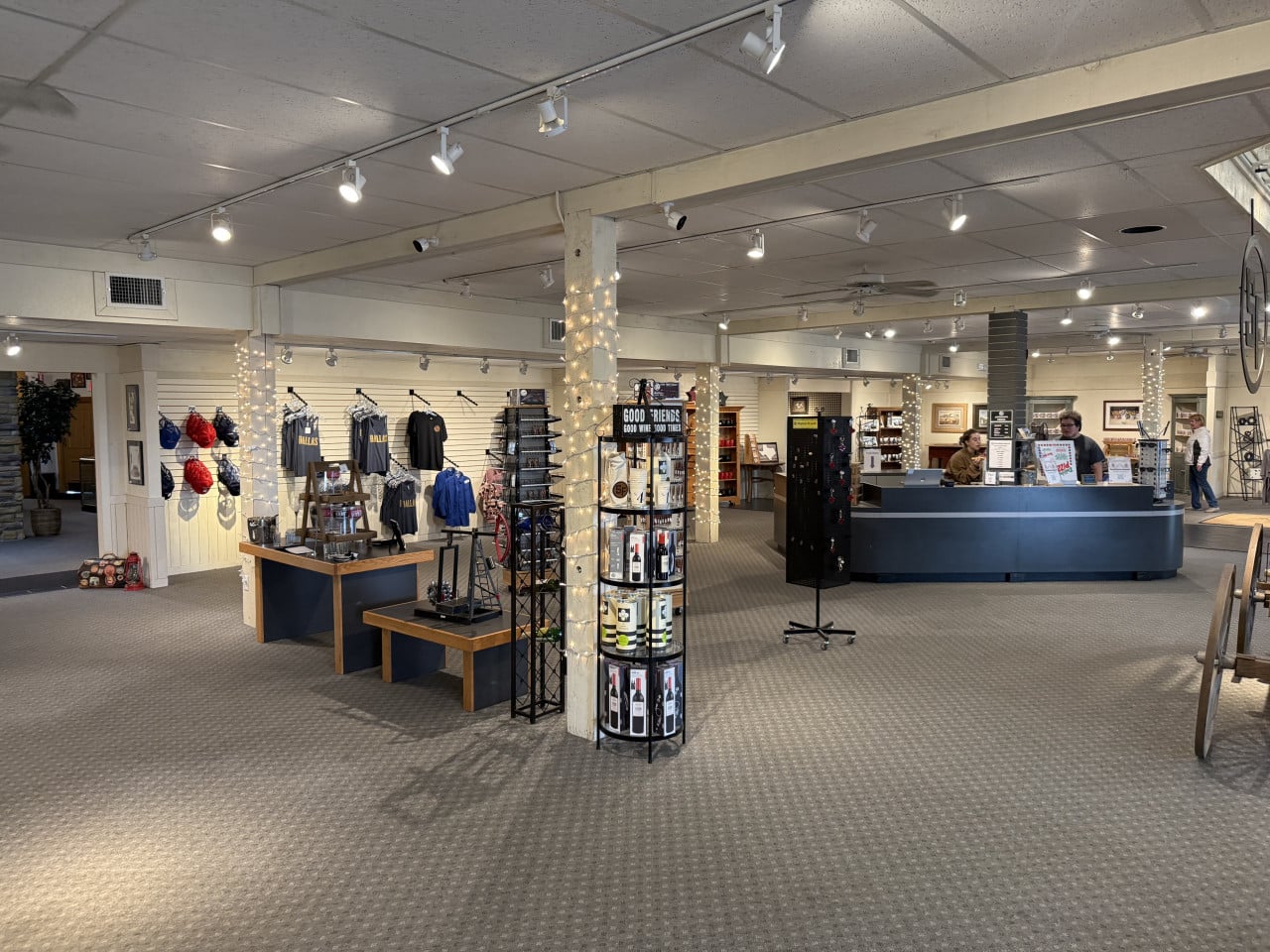 Interiér obchodu na ranči, suvenýry, trička Dallas a nápis GOOD FRIENDS GOOD WINE GOOD TIMES