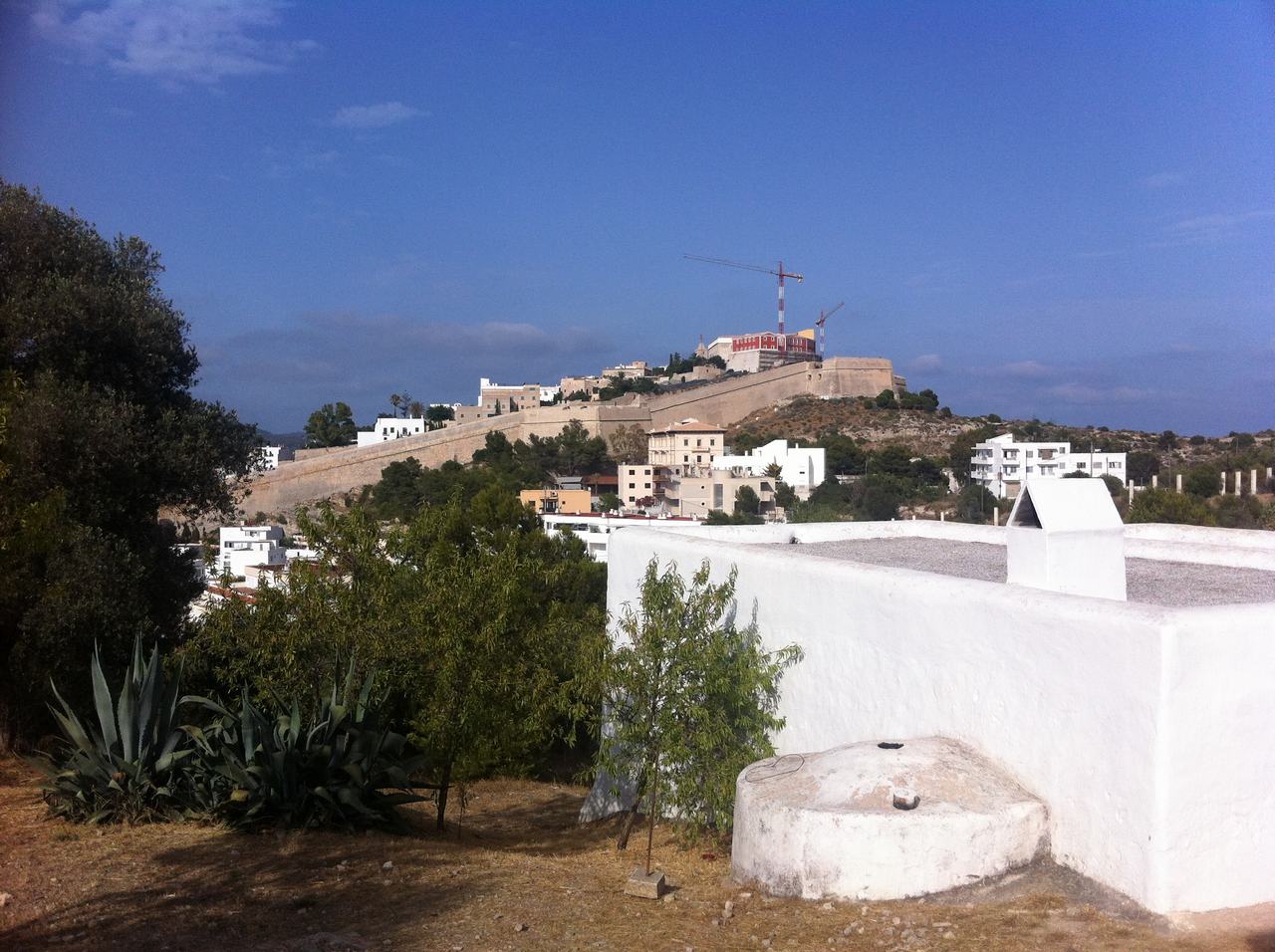 Pohled na pevnost na kopci, bílé domy a jeřáb pod modrou oblohou